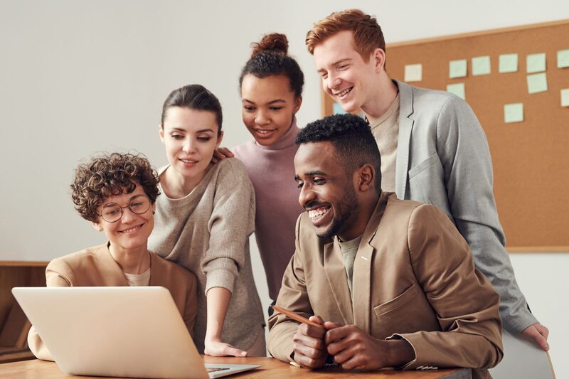 Sales team collaborating around a laptop during a morning campaign briefing